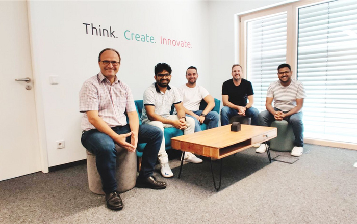 Die Projektbeteiligten sitzen unter der Überschrift Think. Create. an einem Couchtisch.