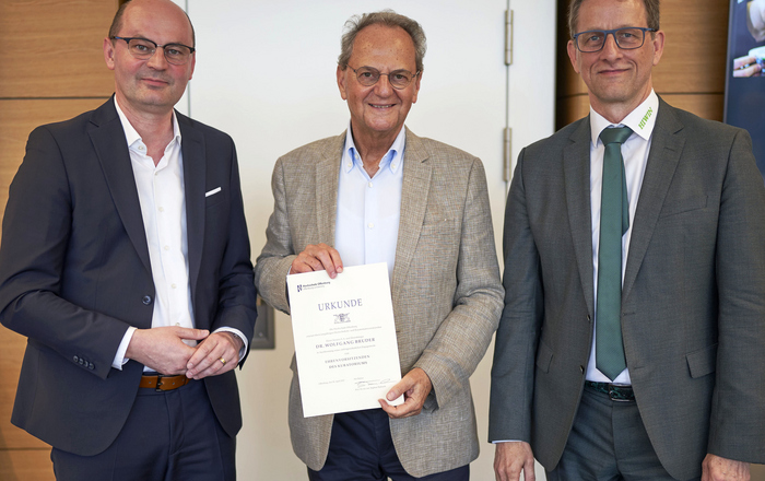 Stephan Trahasch, Dr. Wolfgang Bruder und Werner Mäurer stehen nebeneinander vor einer weißen Tür.