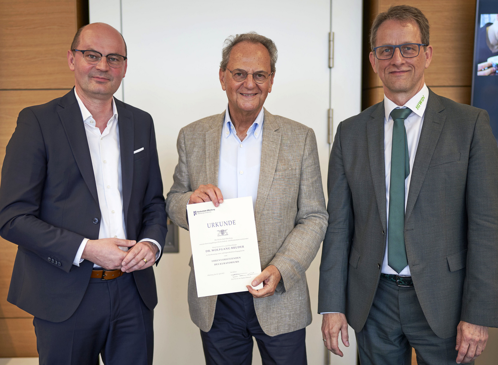 Stephan Trahasch, Dr. Wolfgang Bruder und Werner Mäurer stehen nebeneinander vor einer weißen Tür.