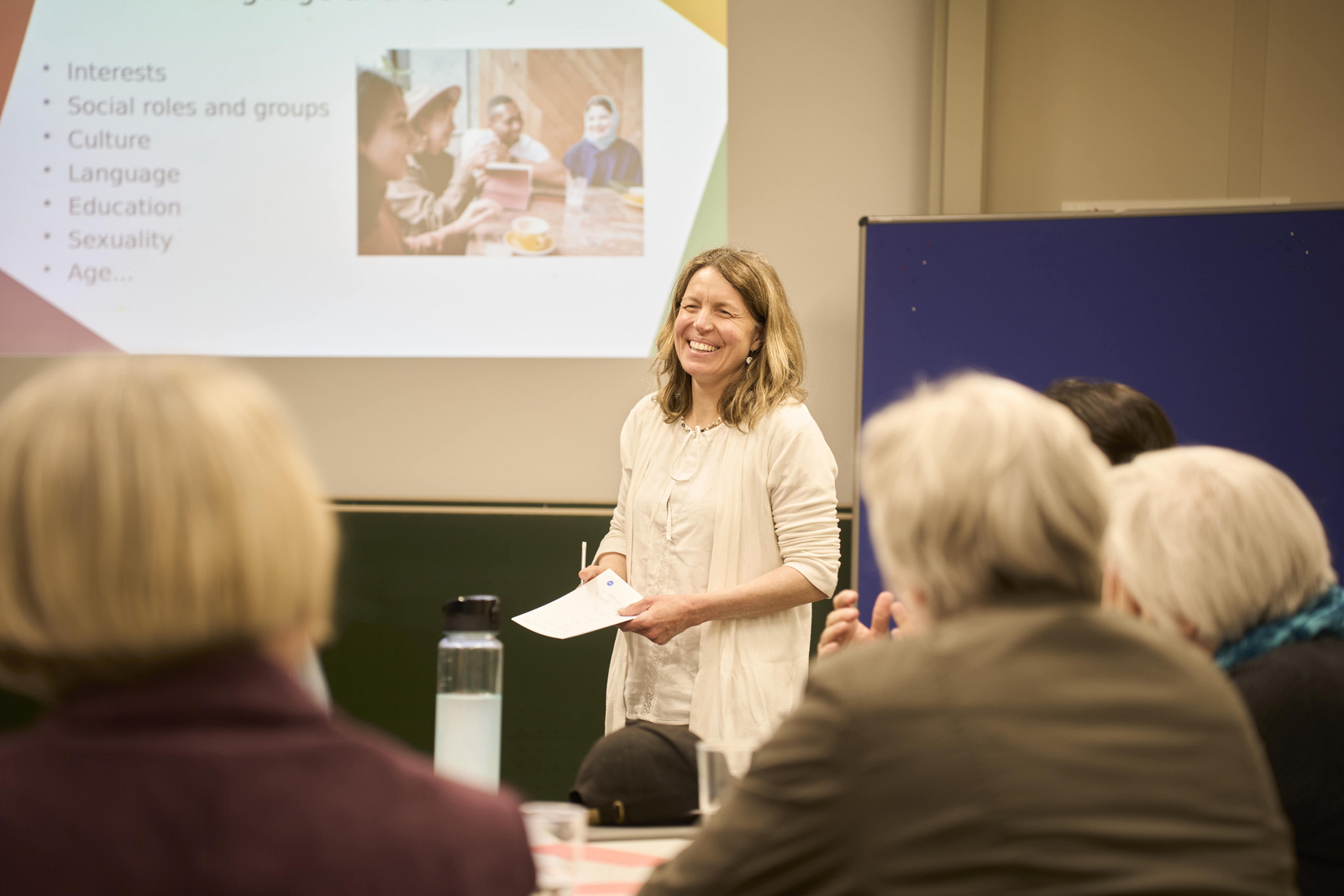 Ein Redner, der an einer Hochschule einen Vortrag über sprachliche Inklusion hält und dabei lächelt 