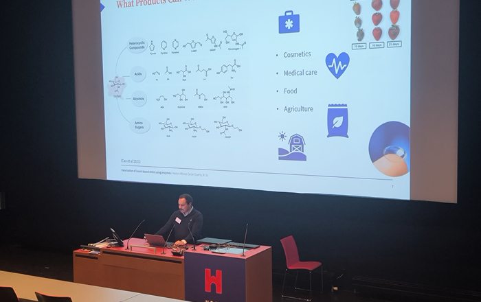 Ein Mann steht in einem Hörsaal vor einer Leinwand an einem Rednerpult