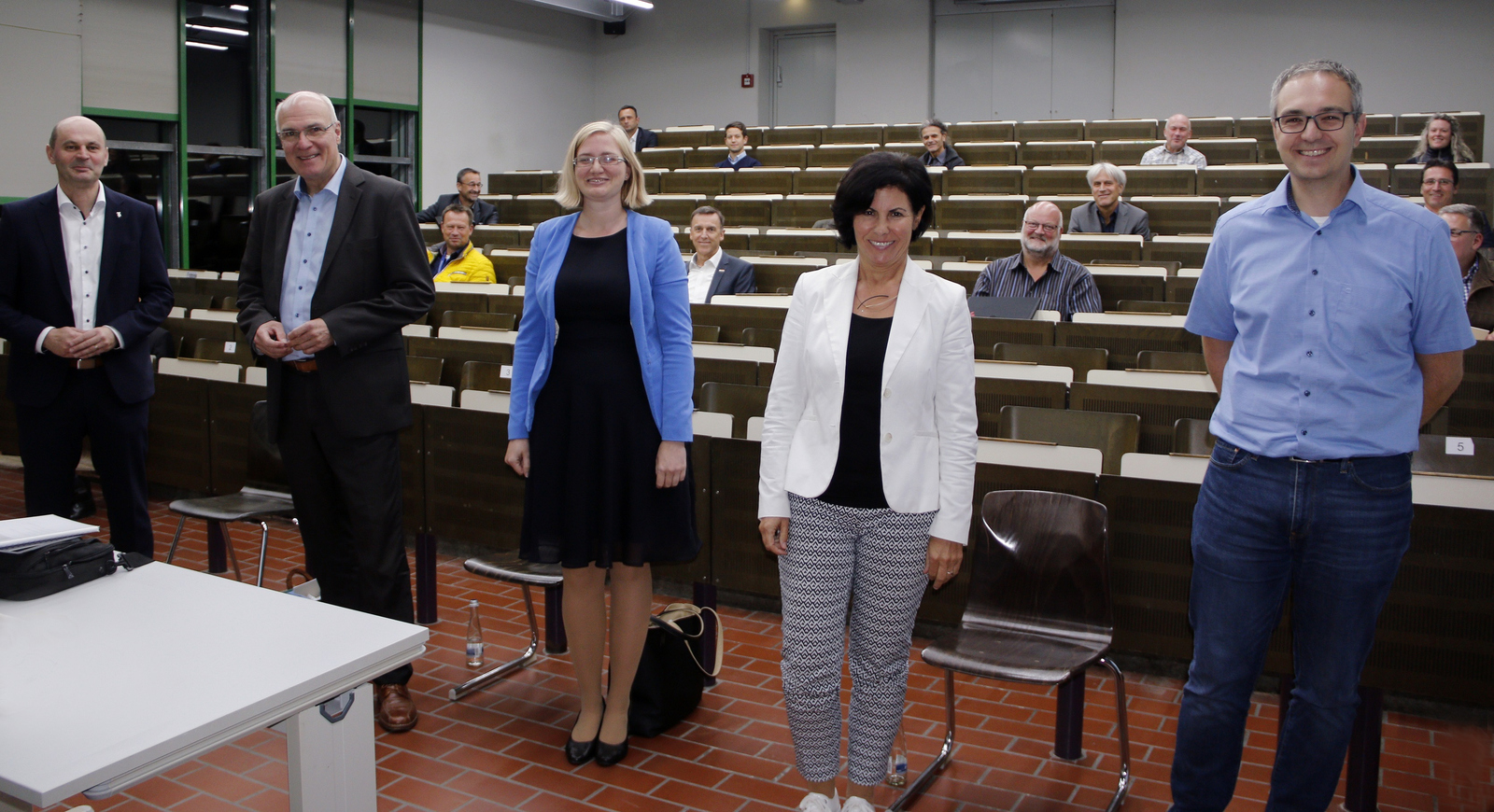 Rektor Prof. Dr. Stephan Trahasch, Helmut Schareck, Julia Migenda, Rita Böcherer und Thomas Hüger (von links) stehen in einem Hörsaal vor den sitzenden Mitgliedern..