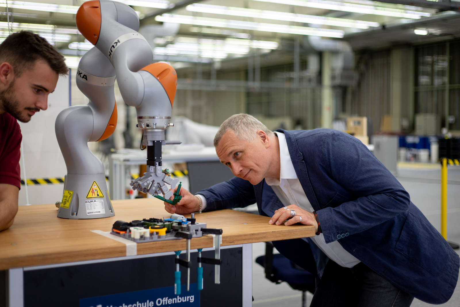 Prof. Dr. Thomas Wendt (rechts) und ein Mitarbeitender (links) arbeiten an einem Koboter 