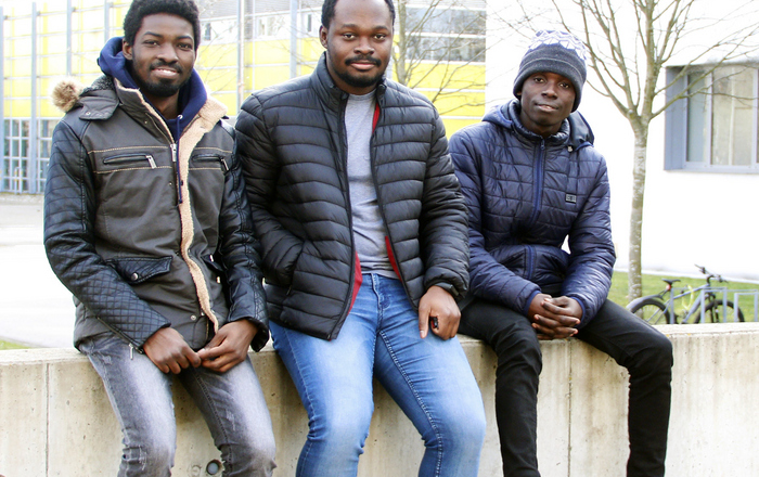 Seth Kotey, Nana Kwadwo Akrasi-Mensah und Robert Antwi von links auf einer Mauer auf dem Campus sitzend.