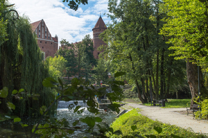 Blick durch einen Park mit Flusslauf auf die Burg Allenstein
