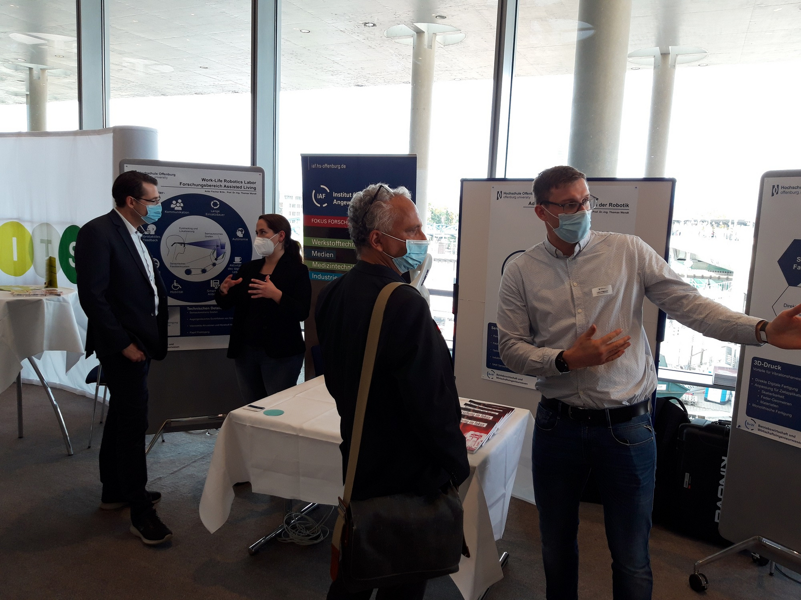 Zwei Doktoranden und zwei Messebesucher unterhalten sich am Stand der Hochschule Offenburg.