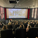 Schülerinnen sitzen im Kino-Saal. Auf der Leinwand läuft der Film
