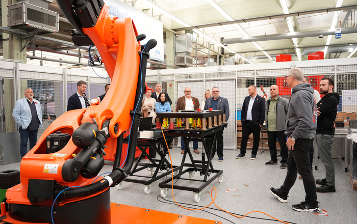 Menschen stehen um einen Industrieroboter herum
