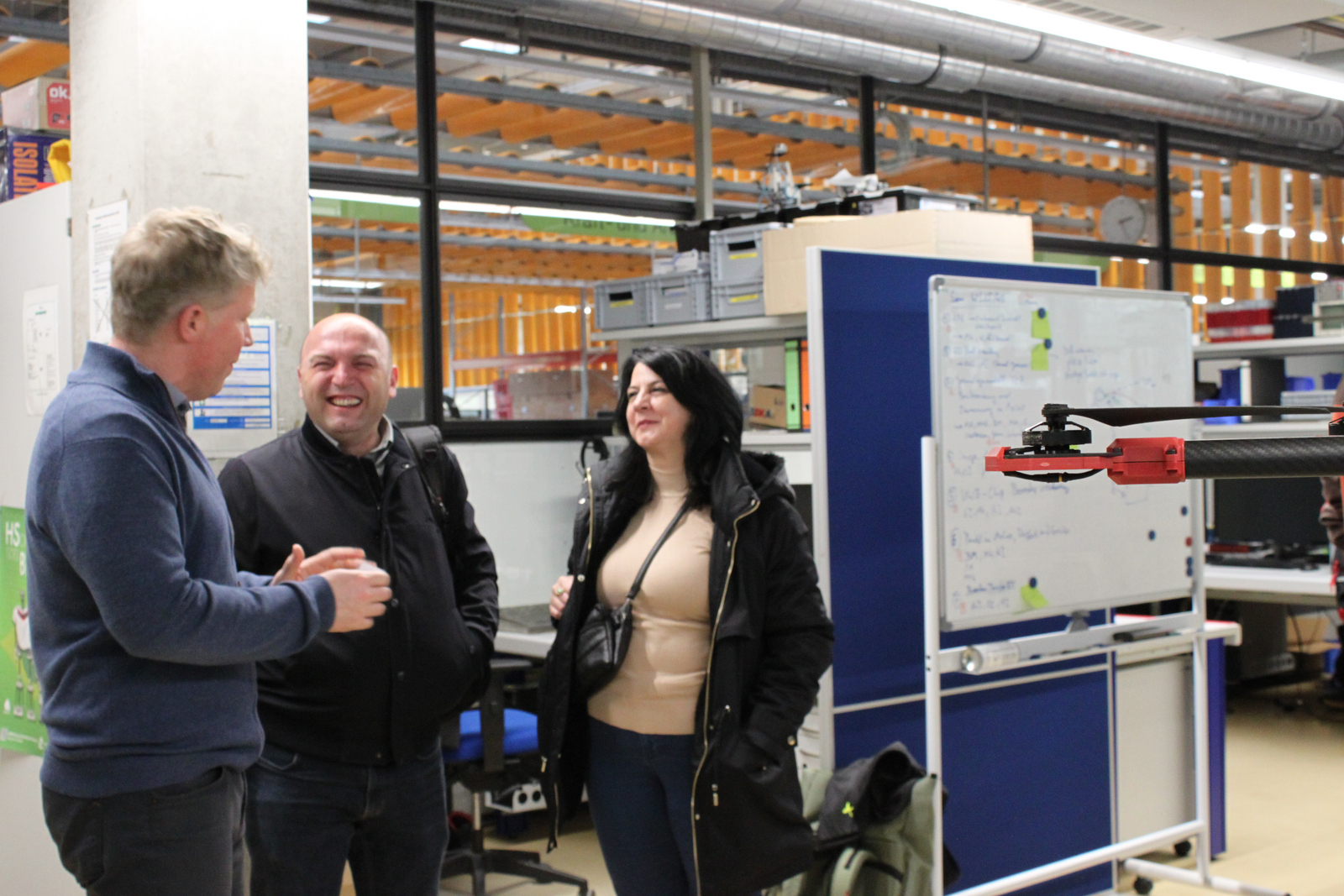 Zwei Männer und eine Frau unterhalten sich in einem Labor