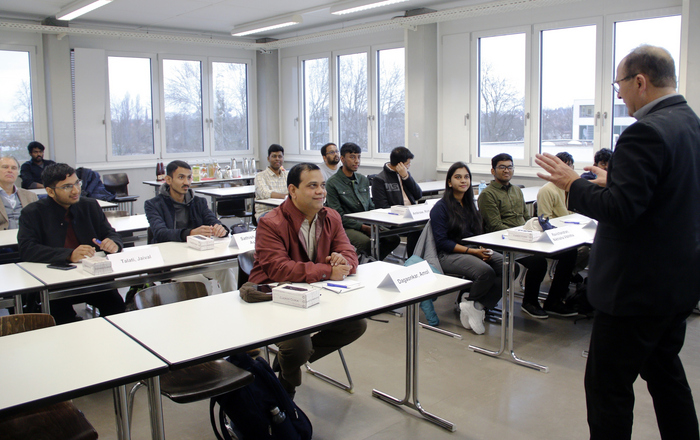 Die Teilnehmenden sitzen in einem Hörsaal und Prof. Sikora steht vor ihnen und hält einen Vortrag