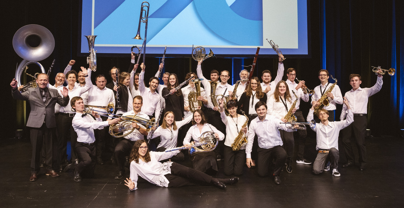 Gruppenfoto des Hochschulorchester, das jubelnd seine Instrumente präsentiert