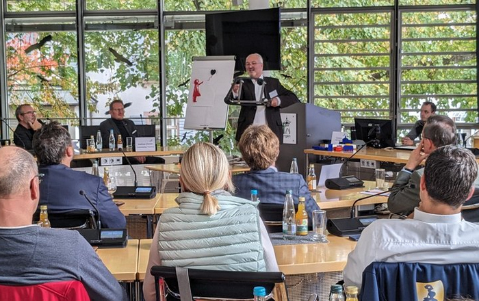 Günther Waibel steht vor einer Gruppe sitzender Menschen