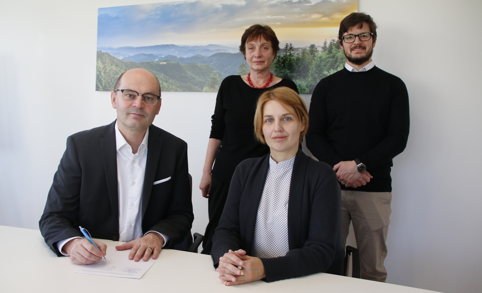 Stephan Trahasch und Oksana Lozovenko sitzen an einem Tisch, Evgenia Sikorski und Alexander Burdumy stehen hinter den beiden.