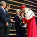 Ein Mann in einer roten Robe mit Hermelinkragen überreicht  mehreren Männern und Frauen eine Medaille