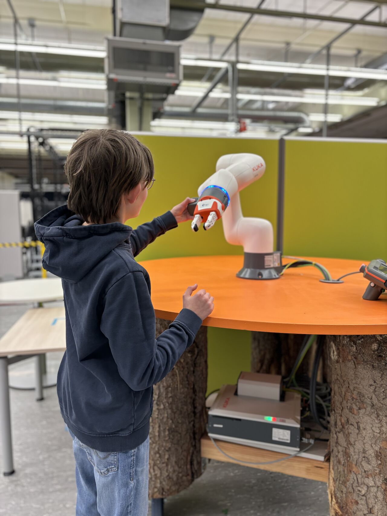 Ein Student interagiert mit einem Roboterarm am WLRI ein Junge interagiert mit einem Roboterarm