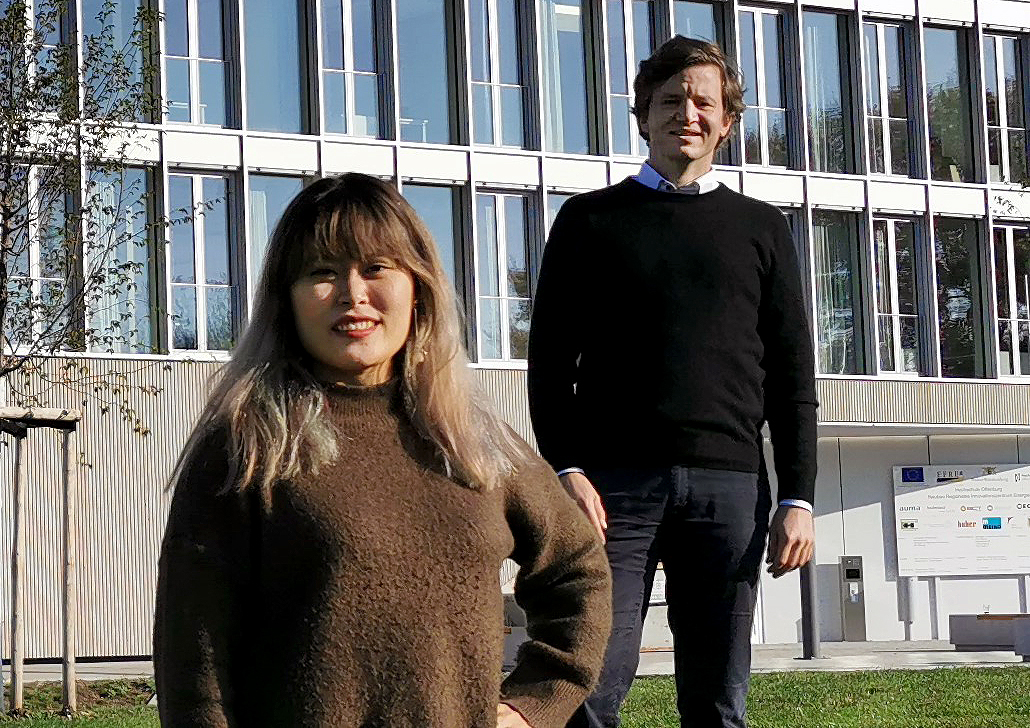 Projektmitarbeiterin Hanhee Kim (links) und Projektleiter Niklas Hartmann (rechts) stehen auf der Wiese vor dem RIZ-Energie.nd Projektleiter an der Hochschule Offenburg für IND-E. 