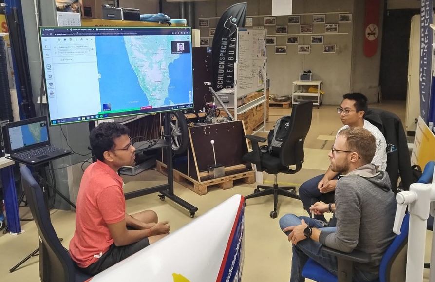 Indische und deustche Studierende sitzen vor einem Bildschirm auf dem ein Karte von Indien zu sehen ist
