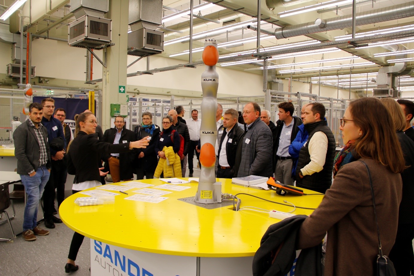 WLRI Mitarbeiterin zeigt den Besuchern des Labors den KUKA-Roboterarm